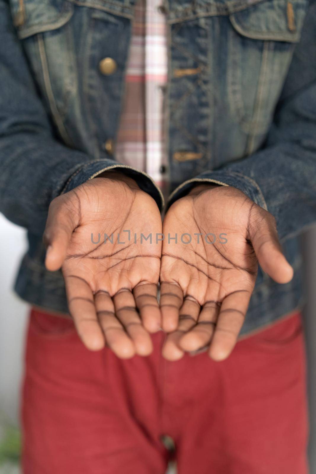 Begging hands of a poor man concept. Open hands of a young african american man wearing denim jacket. Young african american man with outstretched hands begging for money for life.