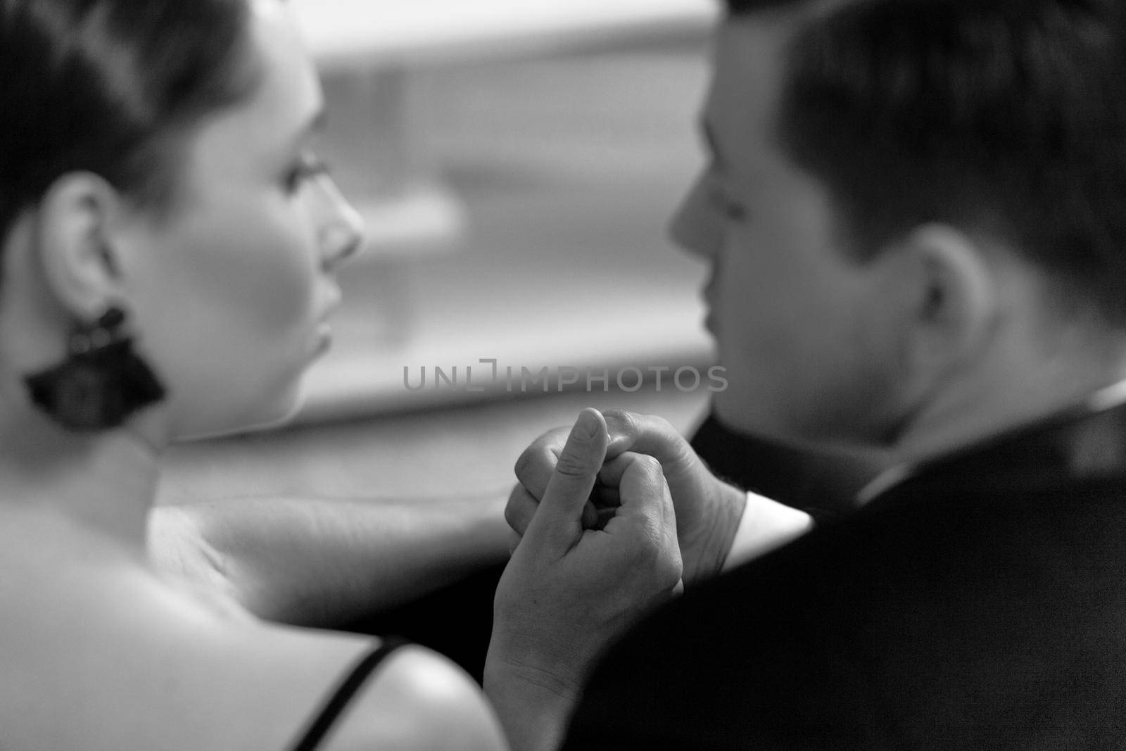 In love Beautiful young couple in home interior sitting back to camera looking at each other. Romance in relationships, love. married couple after a romantic dinner. Black and white photo by LipikStockMedia