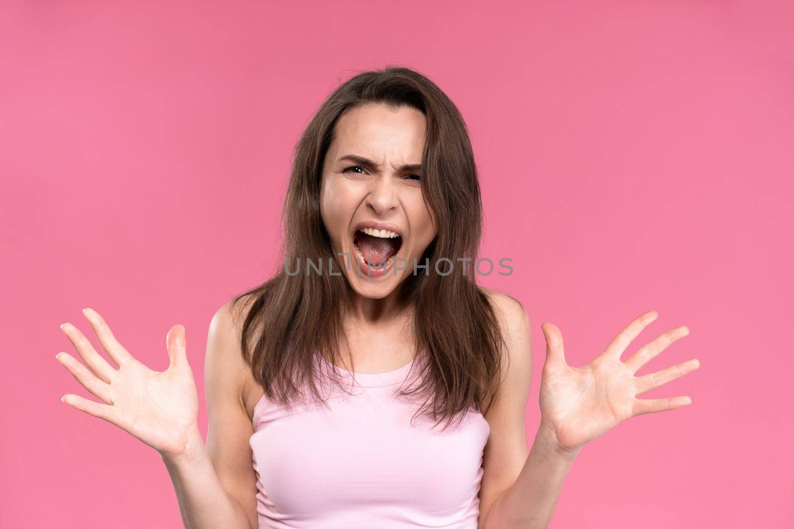 Suffering of headache or migraine young woman in sleeveless pink t-shirt holding her head with eyes shut isolated on pink background. Stressed employee woman in stripe suit. With copy space.