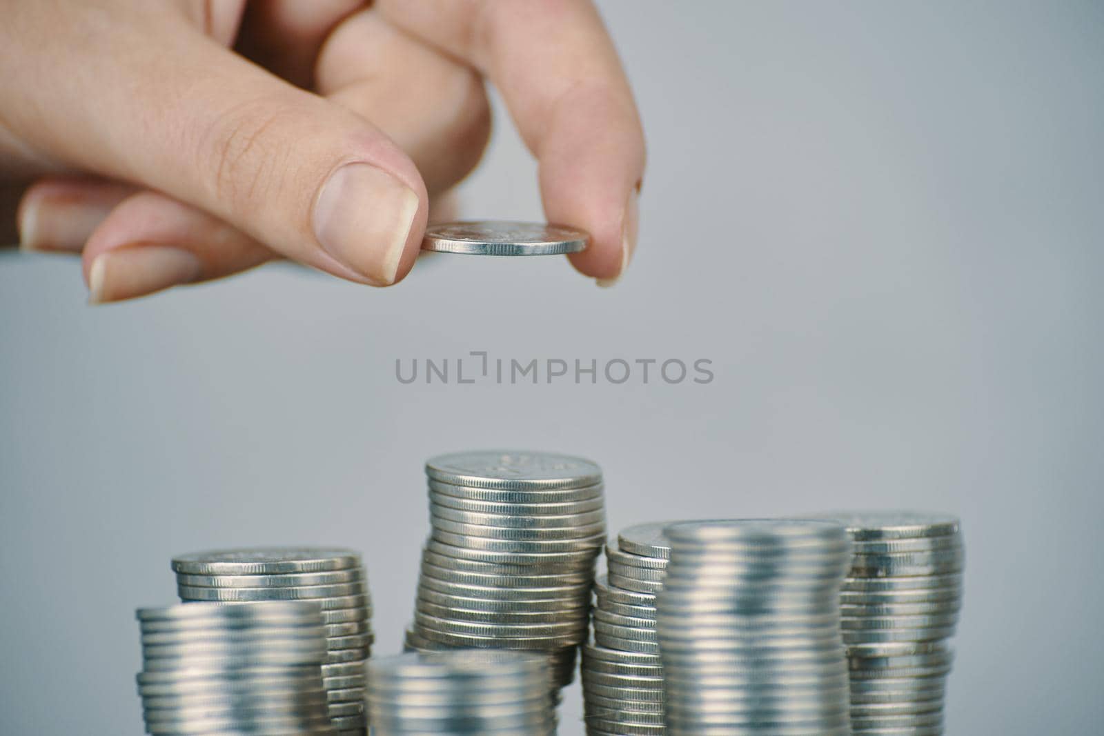 Hand put silver money coins to one of stacks. Expenses and earnings. Different growth of infographics. Concept of business planning and finance. Alms and donations. Small savings.