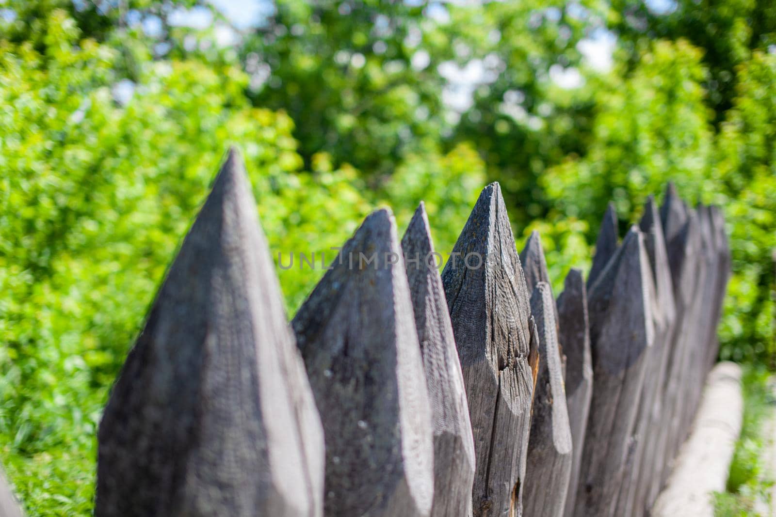 Fence made from sharp wooden stakes. Close-up on an old fence made of stakes, a picket fence, a protective structure near an old wooden fortress, selective focus
