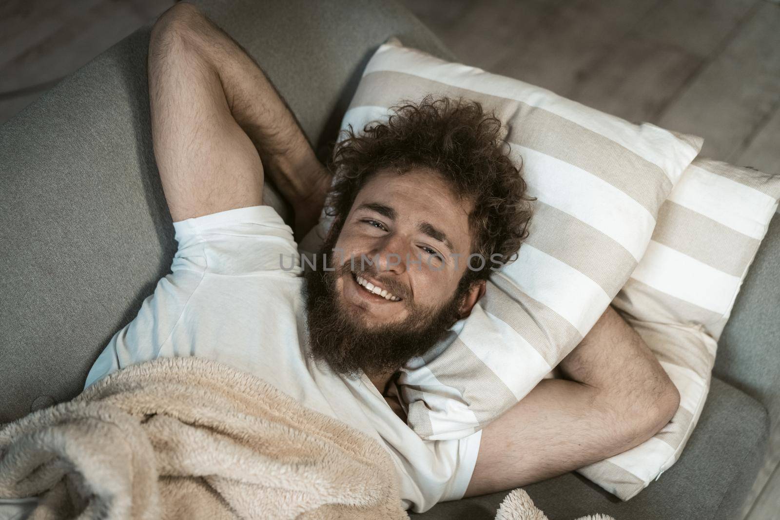 Close up. Portrait of relaxed handsome curly hair man sleeping on the couch or sofa enjoying weekend or quarantine days at home. Weekend relax at home.