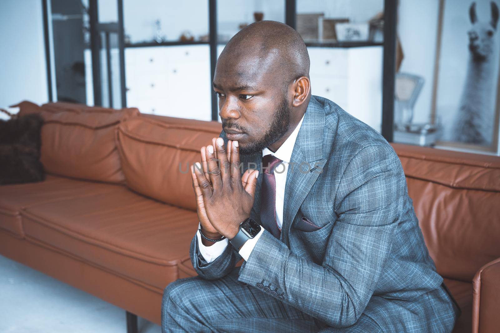 Businessman Pondering of Business Development Strategies. Handsome Man in Classic Suit Sits on a Leather Sofa in the Hall of his Modern Office. Close-up. High quality photo
