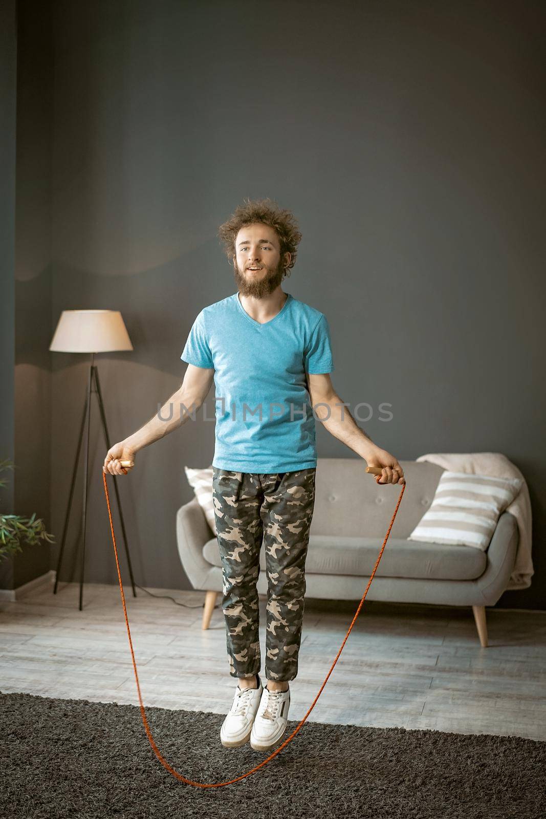 Sporty Male Jumping Rope in Fast Rhythm on the Carpet in his Living Room. He Finds of Sport. High quality photo