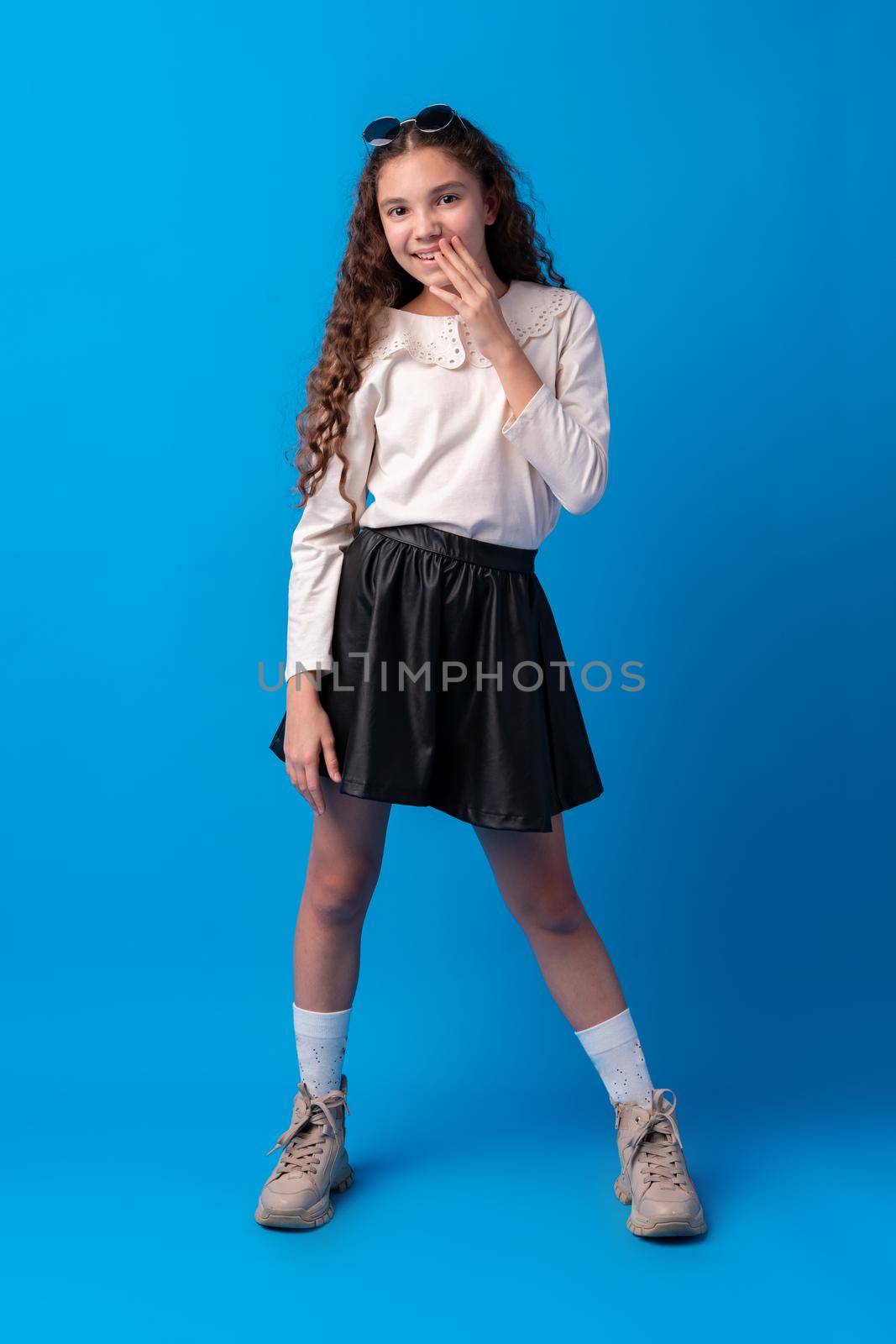 Shocked and surprised young teen girl against blue background, close up