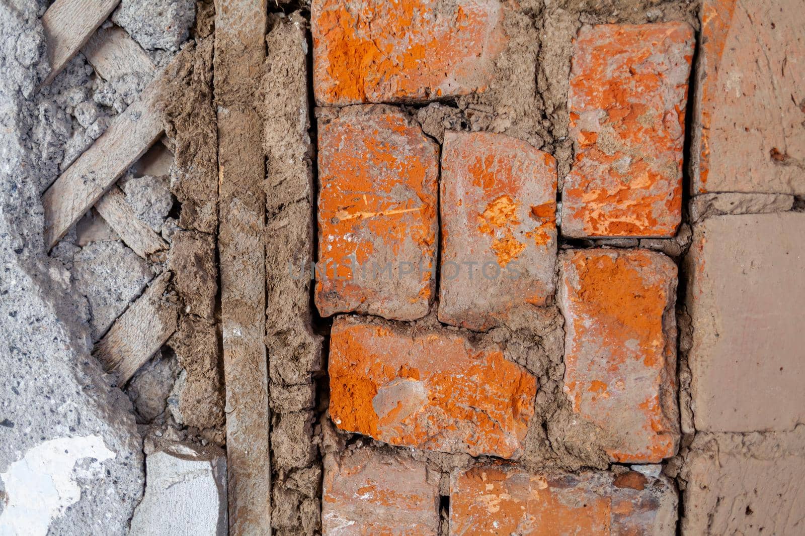 Repair of an old brick wall of a home stove. Different red bricks are laid in the wall after repair. Brick background