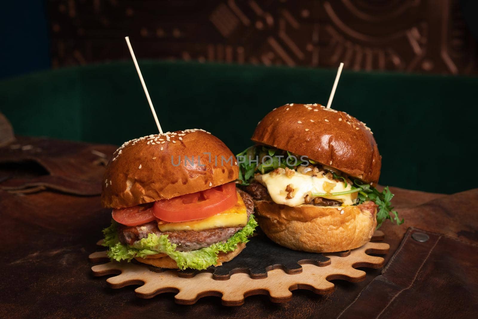 A double serving of fresh beef burgers and one with fried walnuts are served on a decorative wooden part of a simple mechanism. Restaurant concept. Fast food concept. Street food concept.