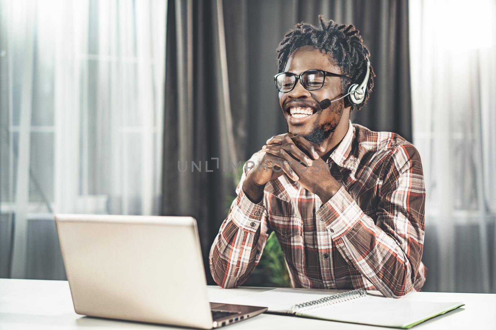 Young English Speaking Teacher is Giving Online Video Lesson. Plan of the Study Semester. Man Sits at the Table and Looks at the Laptop Screen in Headphones with Microphone. Close-up. High quality photo