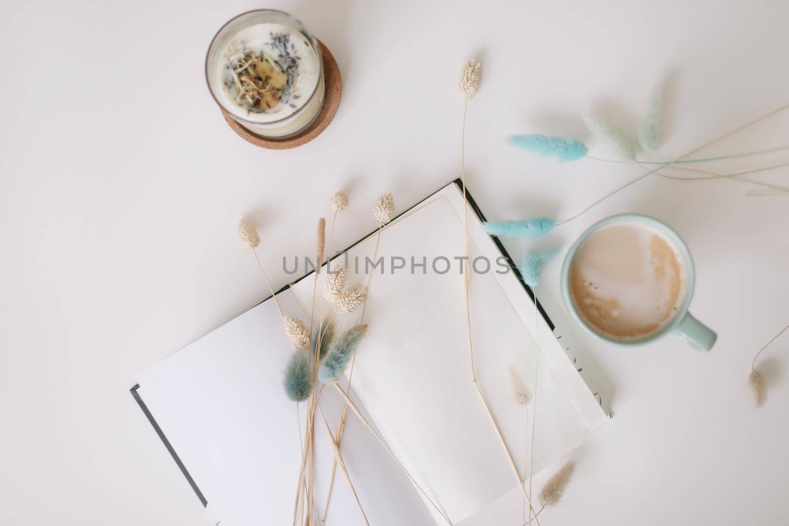 Blank paper sheet, coffee cup and dry flowers on white background. Minimal home workspace desk table. Flat lay, top view, mockup with copy space. by paralisart