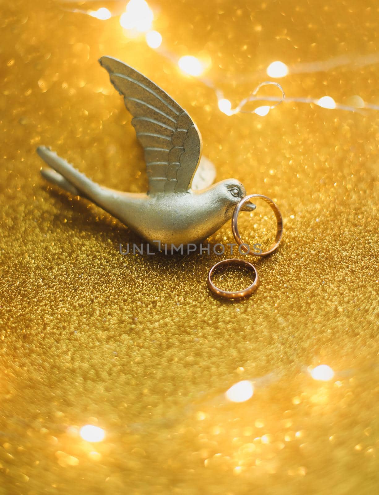 Golden bird holding wedding rings on a golden background. Wedding invitation. valentine gift, sale shopping banner template, copy space  by paralisart