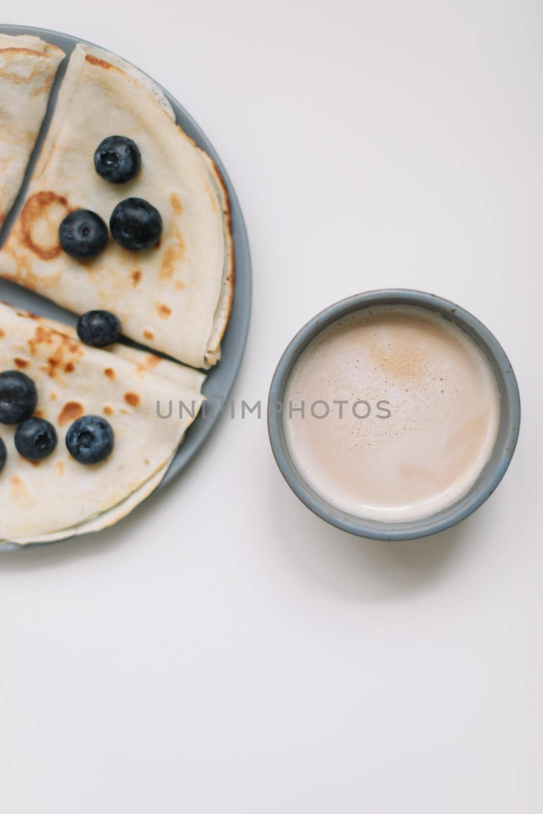 delicious breakfast with pancakes with blueberries on a white table and a coffee cup by paralisart