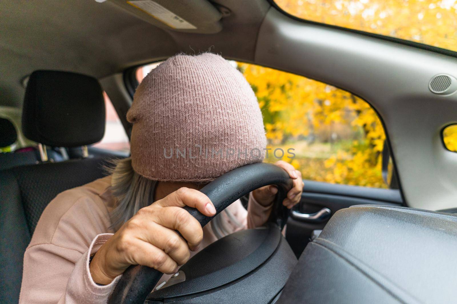 Mature woman in auto crash hit the steering wheel with head. Sleeping exhausted asian woman sleeping in the car. Blond middle aged asian woman in the car. Woman on the road. Business concept.