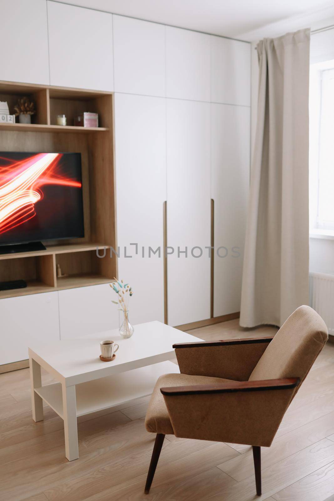 Stylish modern living room interior design with TV, armchair, coffee table and a window with curtains. Minimalistic apartment for rent. 