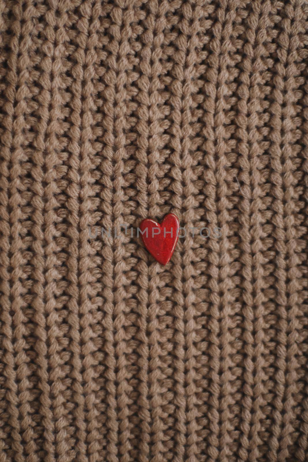 Decorative red heart on beige knitted sweater. Valentines day or love concept