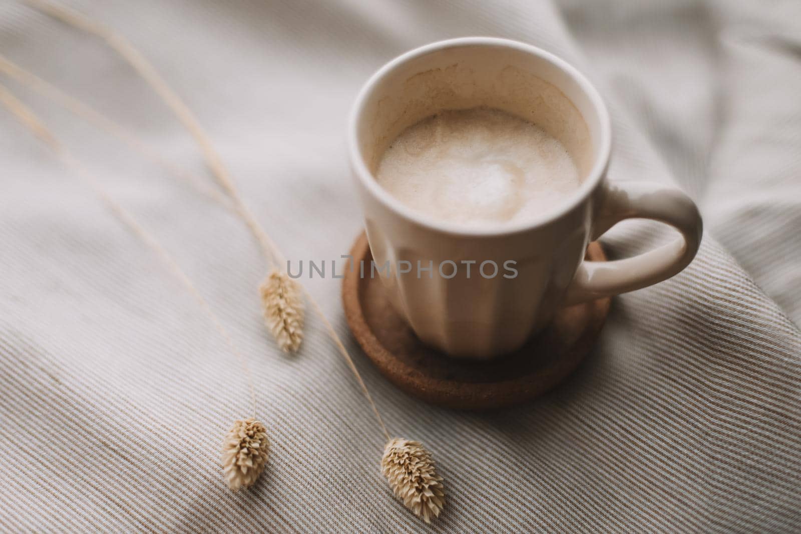 Cup of coffee with milk on beige textile. Still life morning breakfast concept. by paralisart