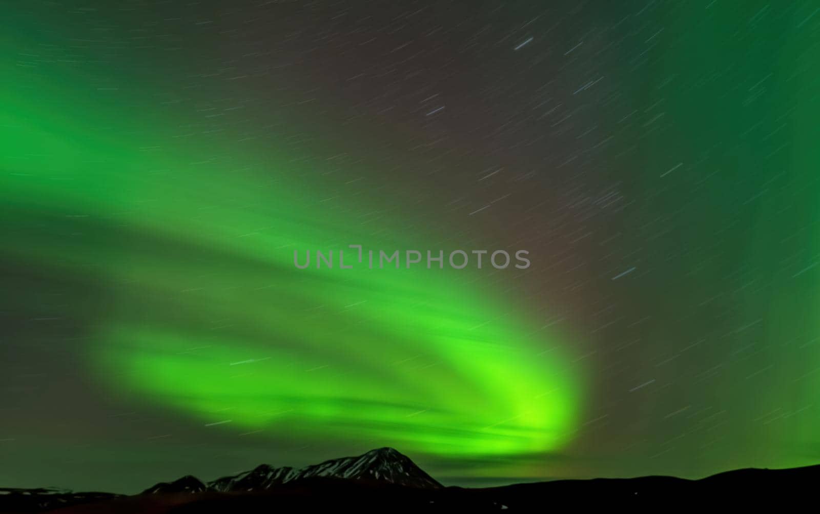 Aurora borealis with star trail and mountain peak