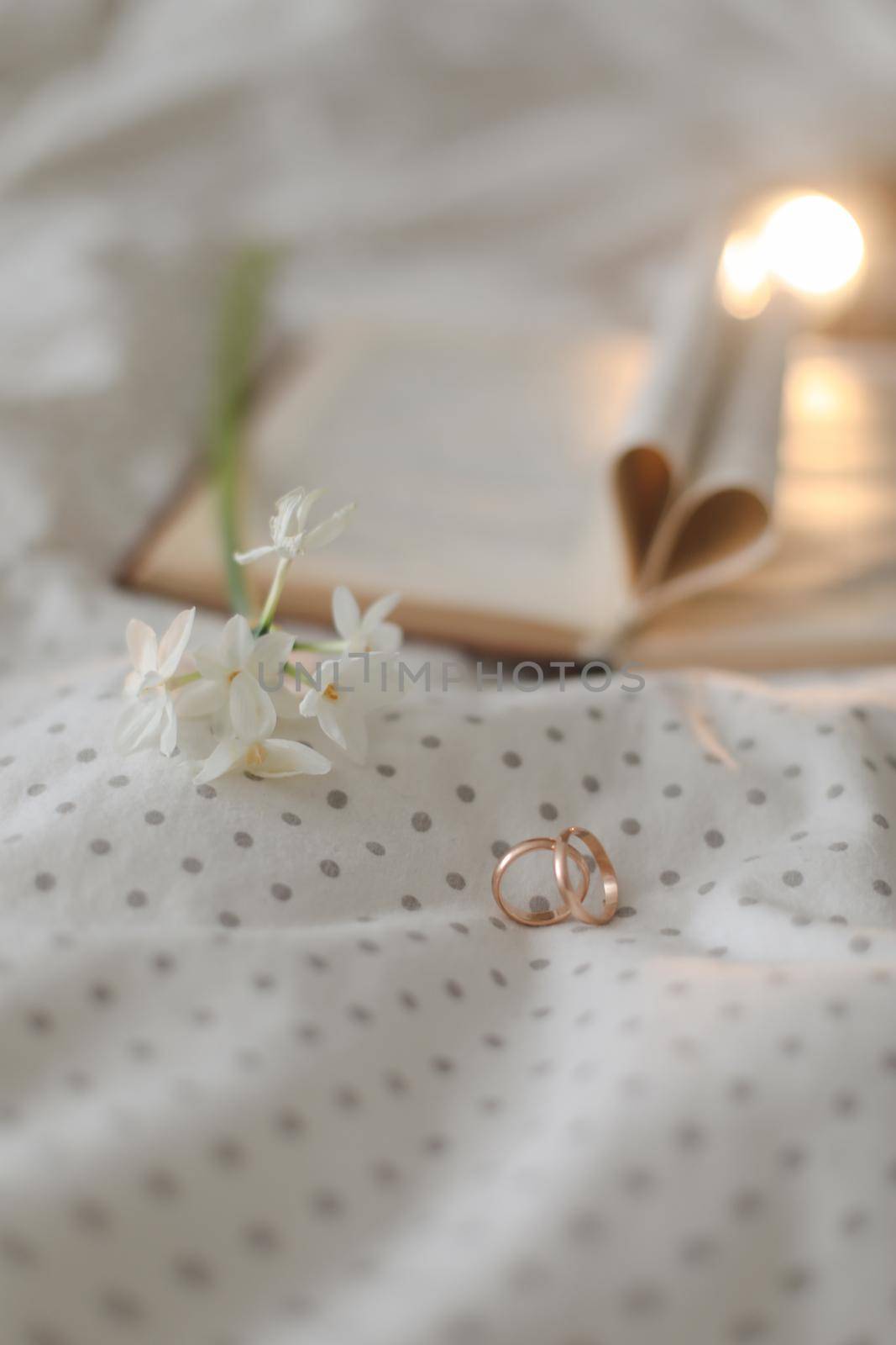 Golden ring and open book with folded sheets in heart shape in bed. Wedding concept, Happy Valentine's Day.