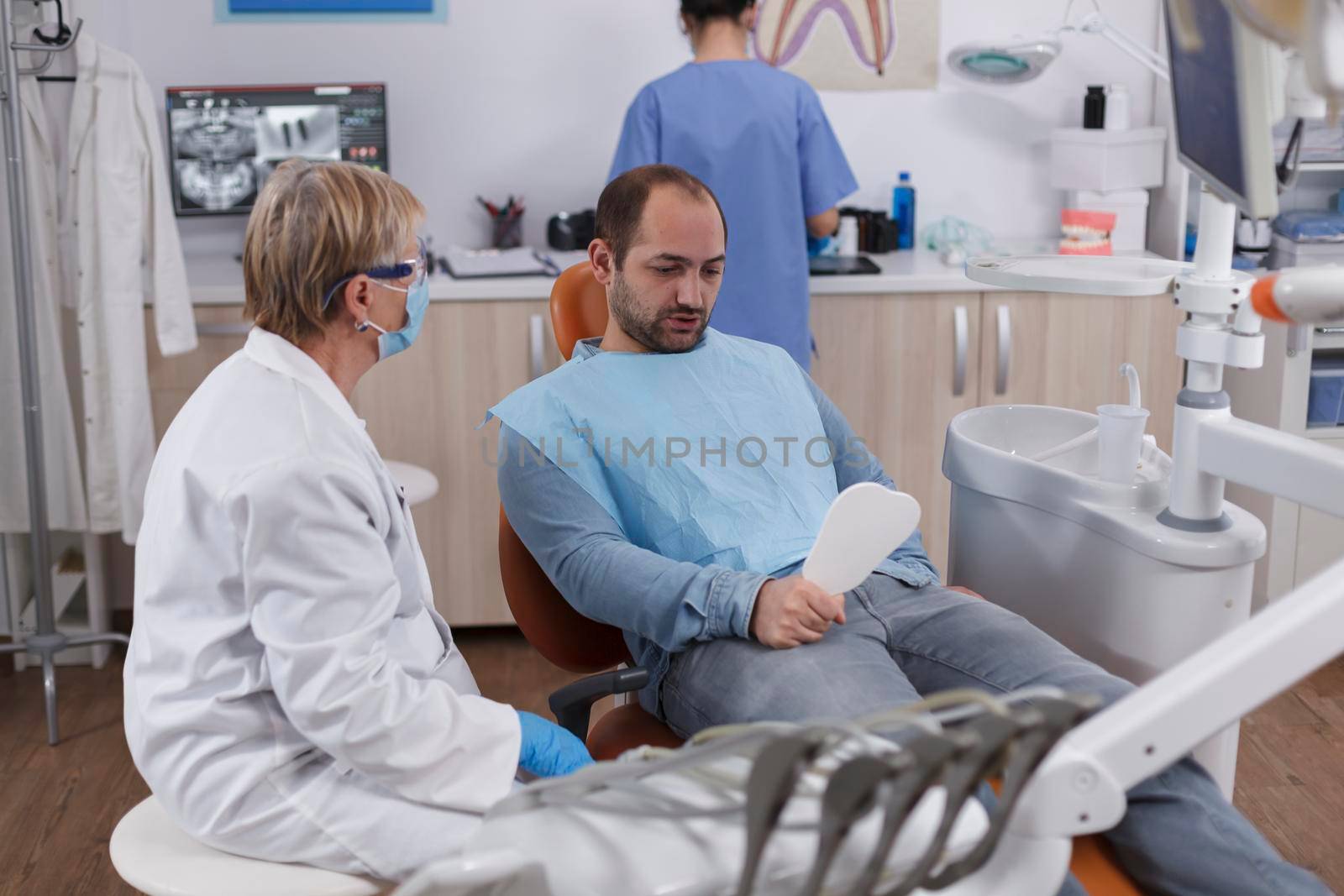 Patient holding mirror looking at teeth procedure after caries infection by DCStudio