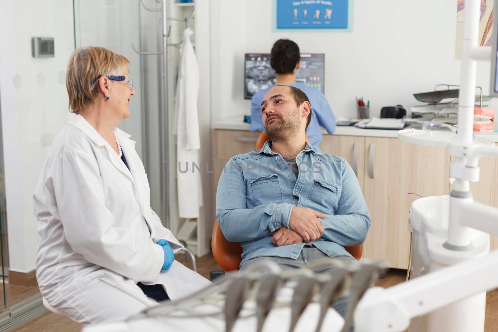 Specialist dentist doctor explaining oral hygiene to man patient discussing medical treatment to prevent caries infection during stomatological examination in dentistry office. Medicine services