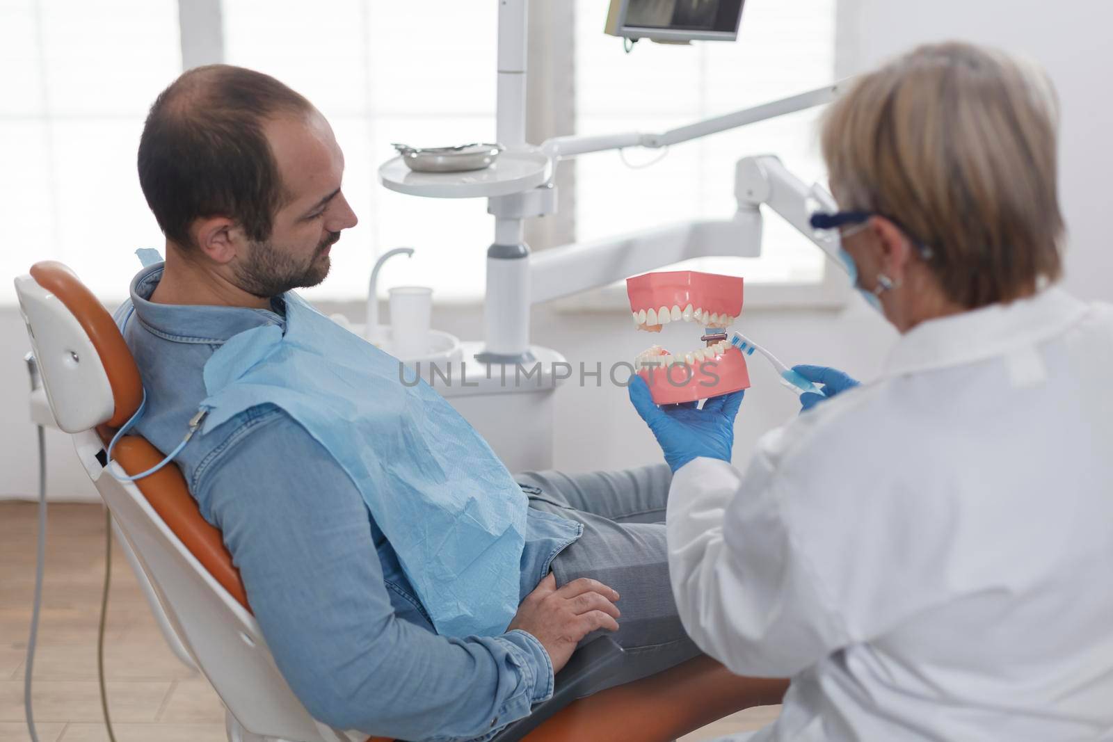 Dpecialist orthodontist showing ceramic jaw model to patient with toothache discussing carier treatment during stomatology consultation in dentistry office room. Doctor woman explaining oral hygiene