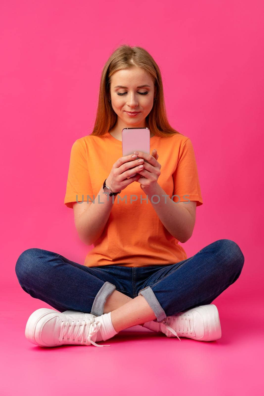 Portrait of a young woman using mobile phone over color background, close up