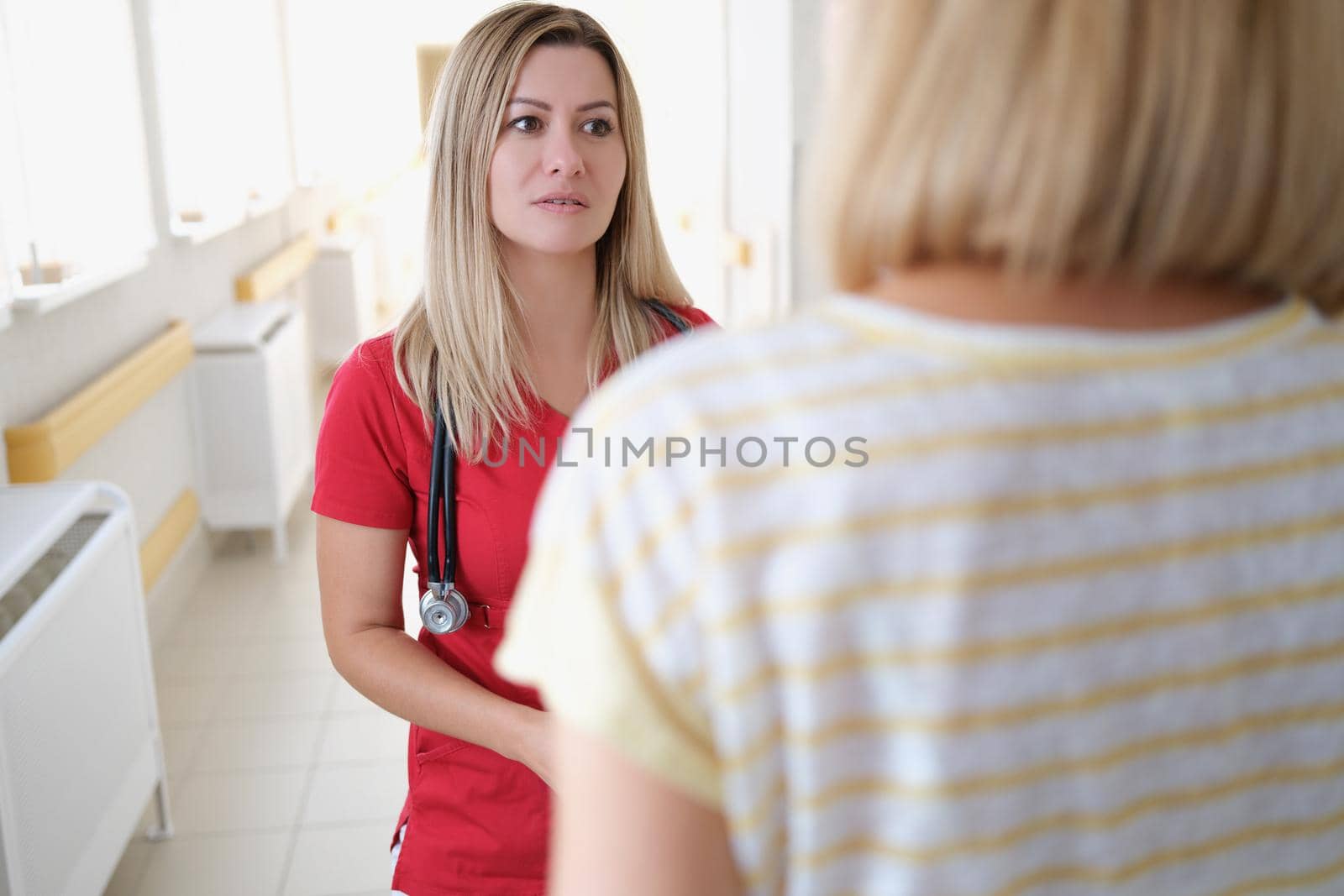 Doctor communicating with female patient in clinic. Quality medical care concept