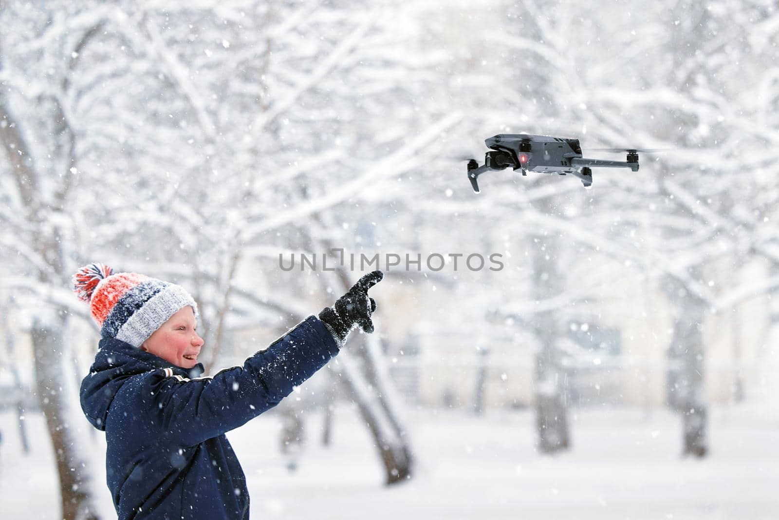 Teenager boy dressed winter jacket and modern digital drone DJI Mavic, flying in snow conditions. DJI Mavic 3 most portable drones with Hasselblad camera. 25.01.2022 Rostov-on-Don, Russia.