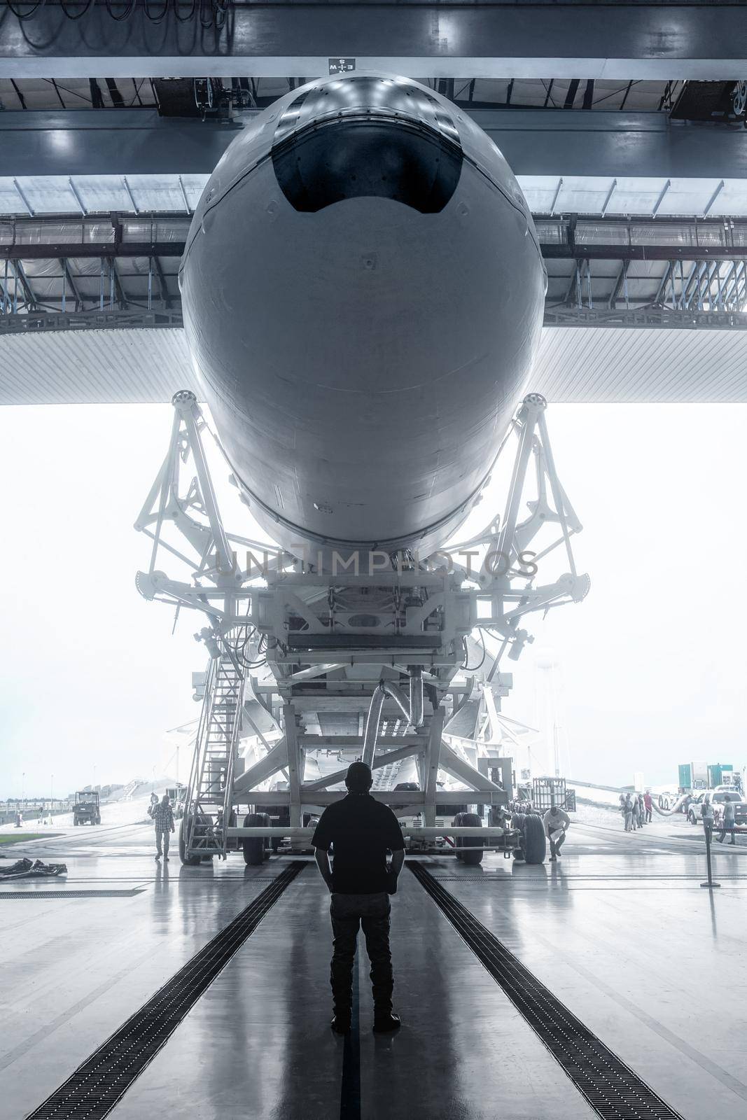 Space engineer looks at a built spacecraft. Rocket with spacecraft, rolls out of the hangar. Space launch preparation. rocket, inside the maintenance hangar. Elements of this image furnished by NASA.