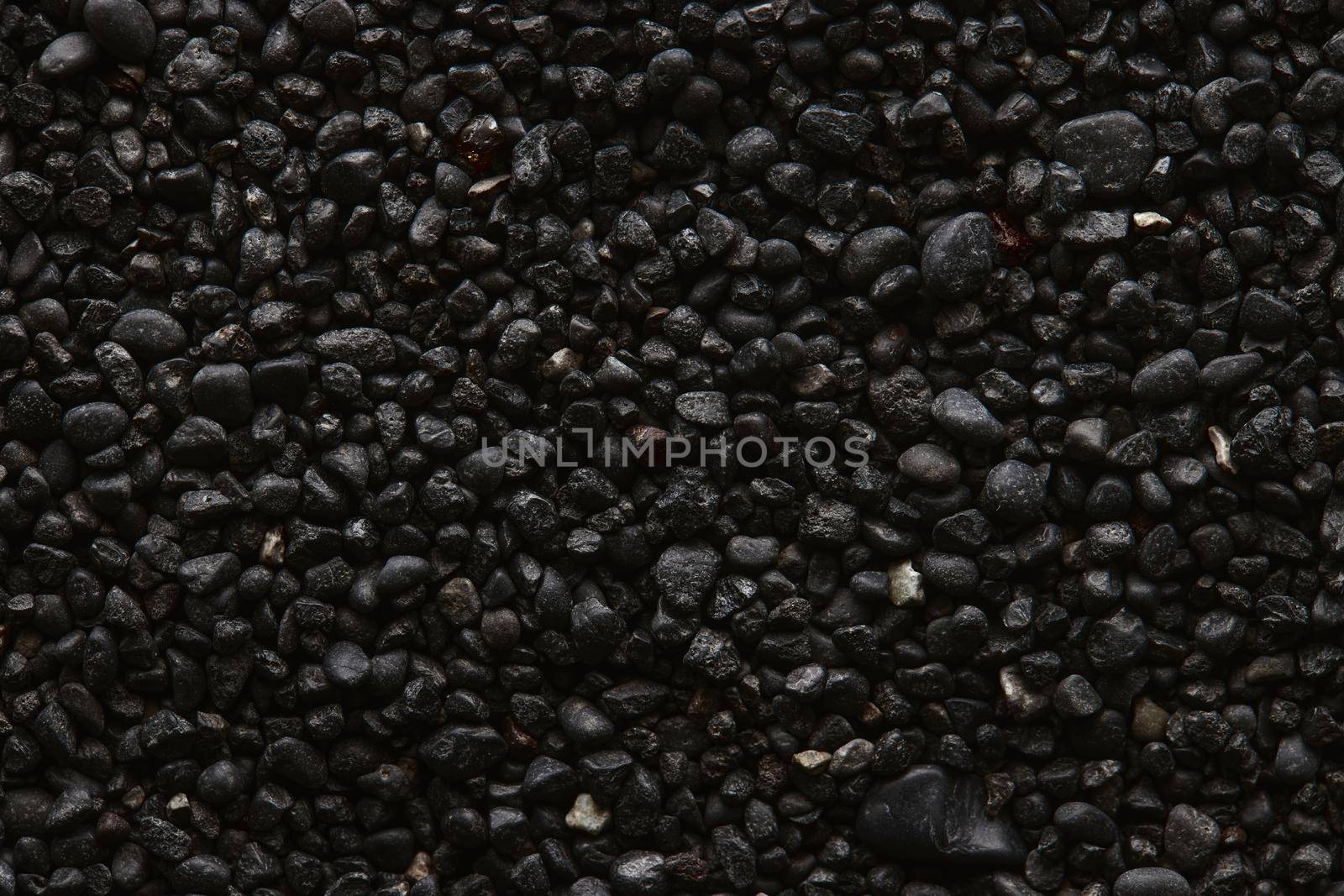 Texture of black volcanic sand for background. Black Sand beach macro photography. Close-up view of volcanic sand surface. Icelandic Black Sand macro photography. Black pebble background.
