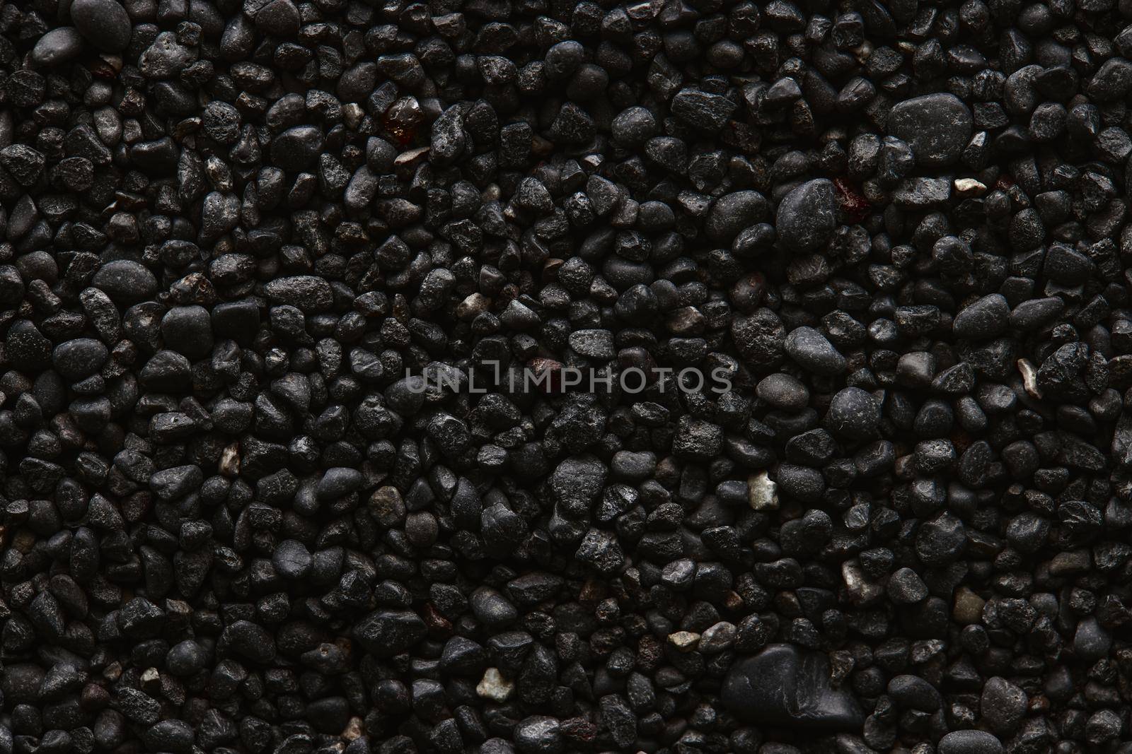 Texture of black volcanic sand for background. Black Sand beach macro photography. Close-up view of volcanic sand surface. Icelandic Black Sand macro photography. Black pebble background.