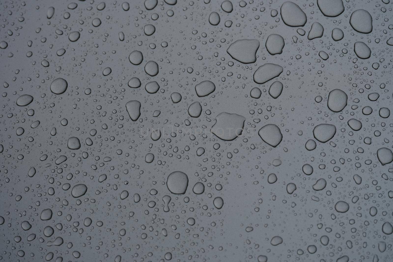 Raindrops on dark glass on rainy day closeup background by kuprevich