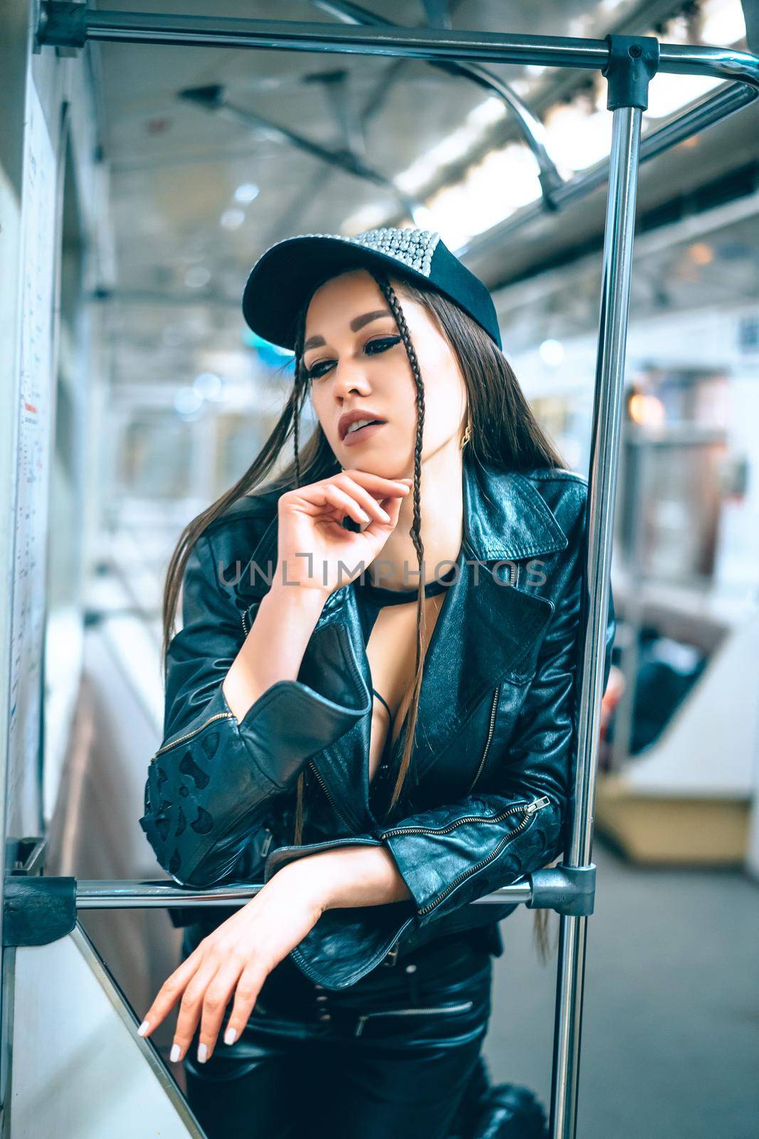 delightful Woman in stylish trendy clothes stands in a beautiful pose in a subway car. disco girl returns home at night from a party by subway. Close-up Portrait by LipikStockMedia