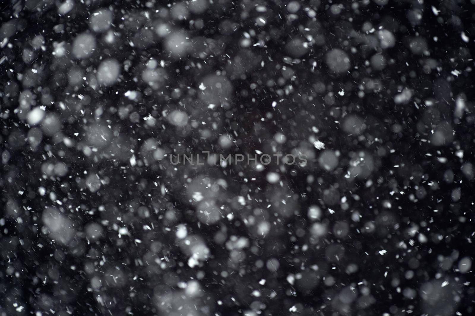 Snowfall on black background. Snowfall in the night sky, real snowflakes fall in the night.