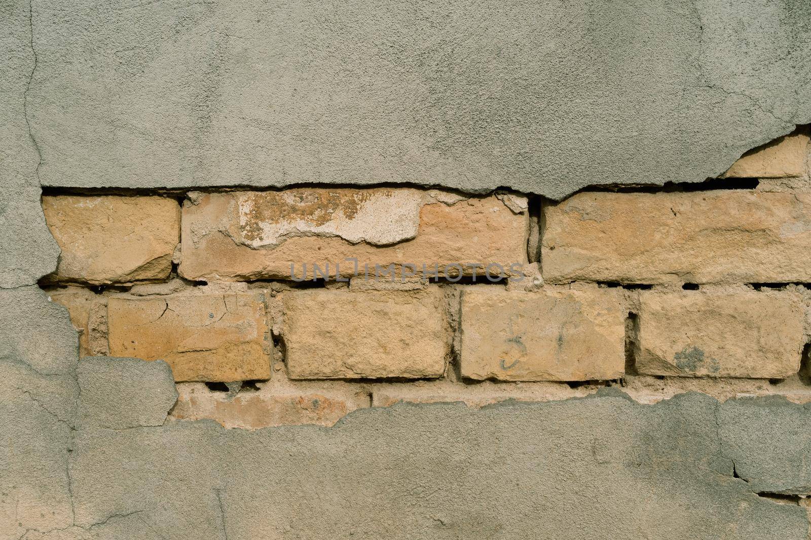 Texture of outer wall with fallen plaster. Old building with falling off plaster. Background of brick wall pattern.