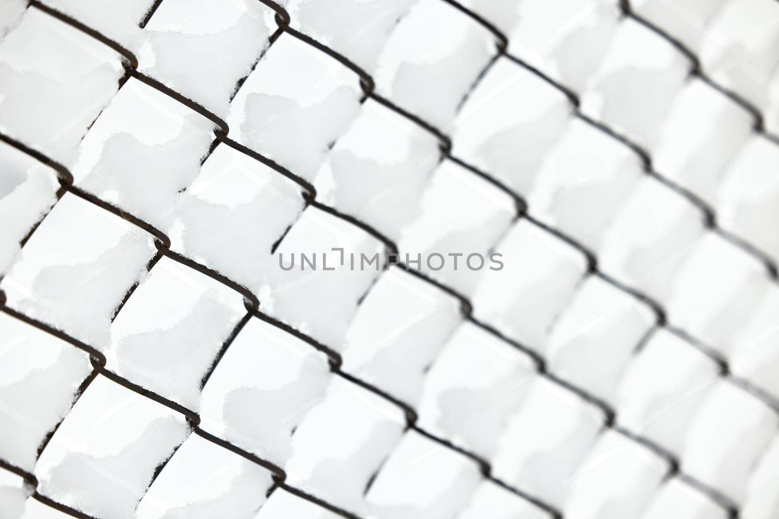 Snow on a mesh fence close-up, snow fence. Abstract winter background. Snow on a wire fence.