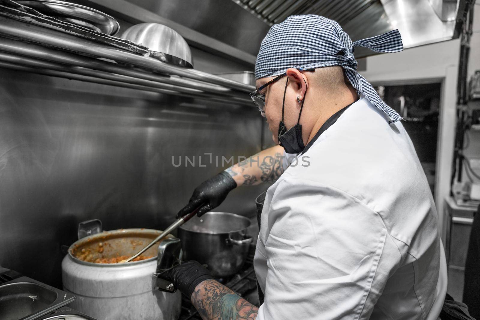 Side view of female chef working in commercial kitchen by HERRAEZ