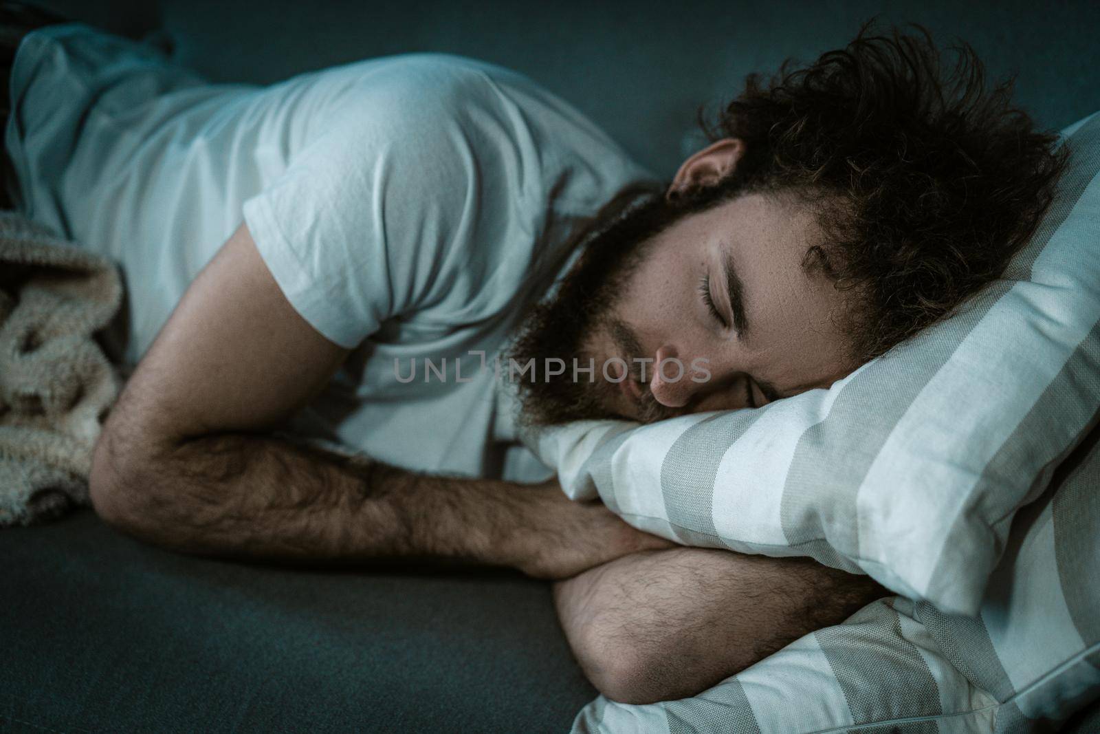 Tired Man is Fast Asleep in his Bed on a Pillow. Sleeping Man in a White T-shirt, Night Sleep, Lunchtime Dream. Break For Sleep. Close-up. High quality photo