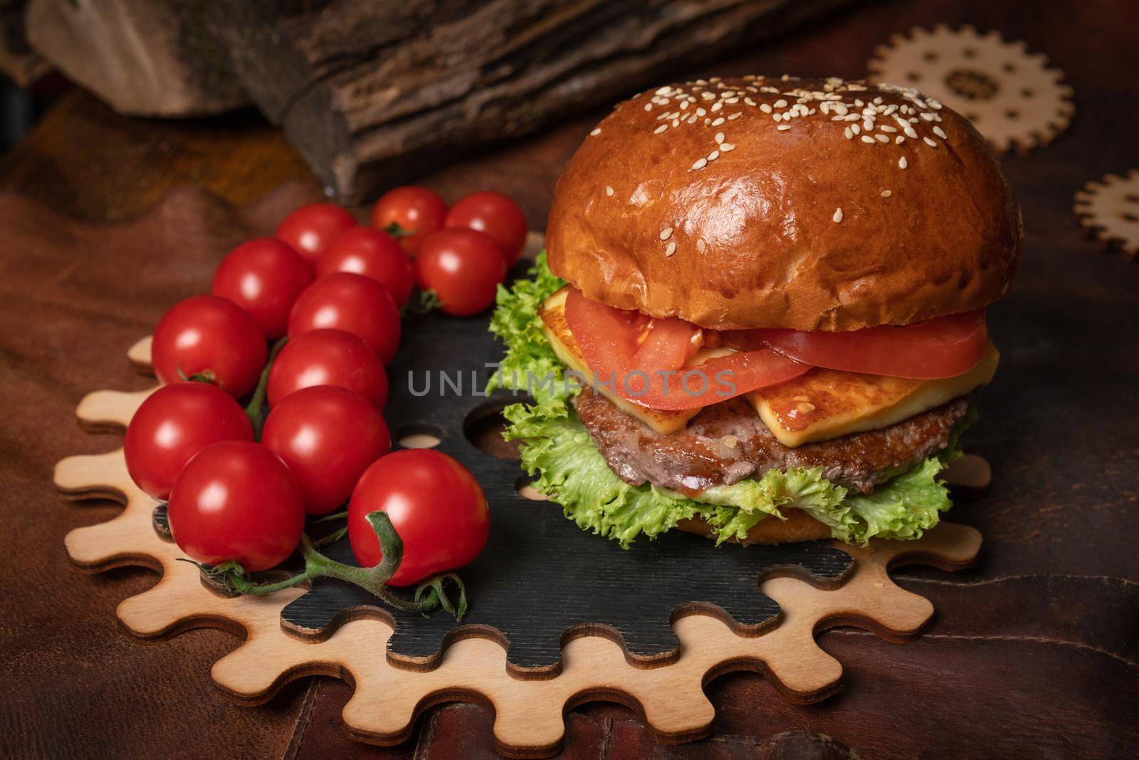 Commercial footage of fresh beef burger with a branch of fresh cherry tomatoes served on a decorative wooden part of a simple mechanism. Restaurant concept. Fast food concept. Street food concept.