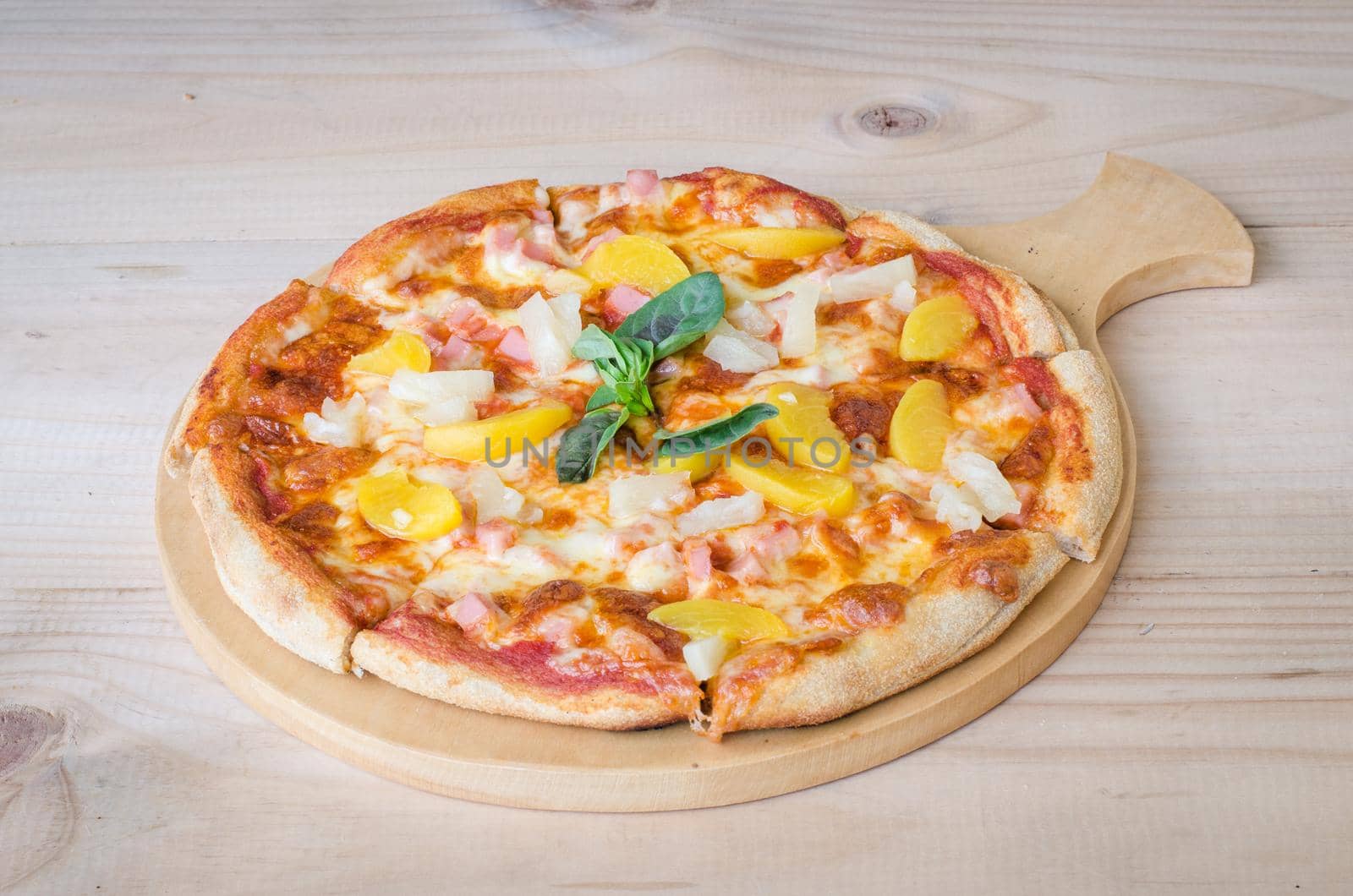 Hawaiian pizza with pineapple and ham on wooden table