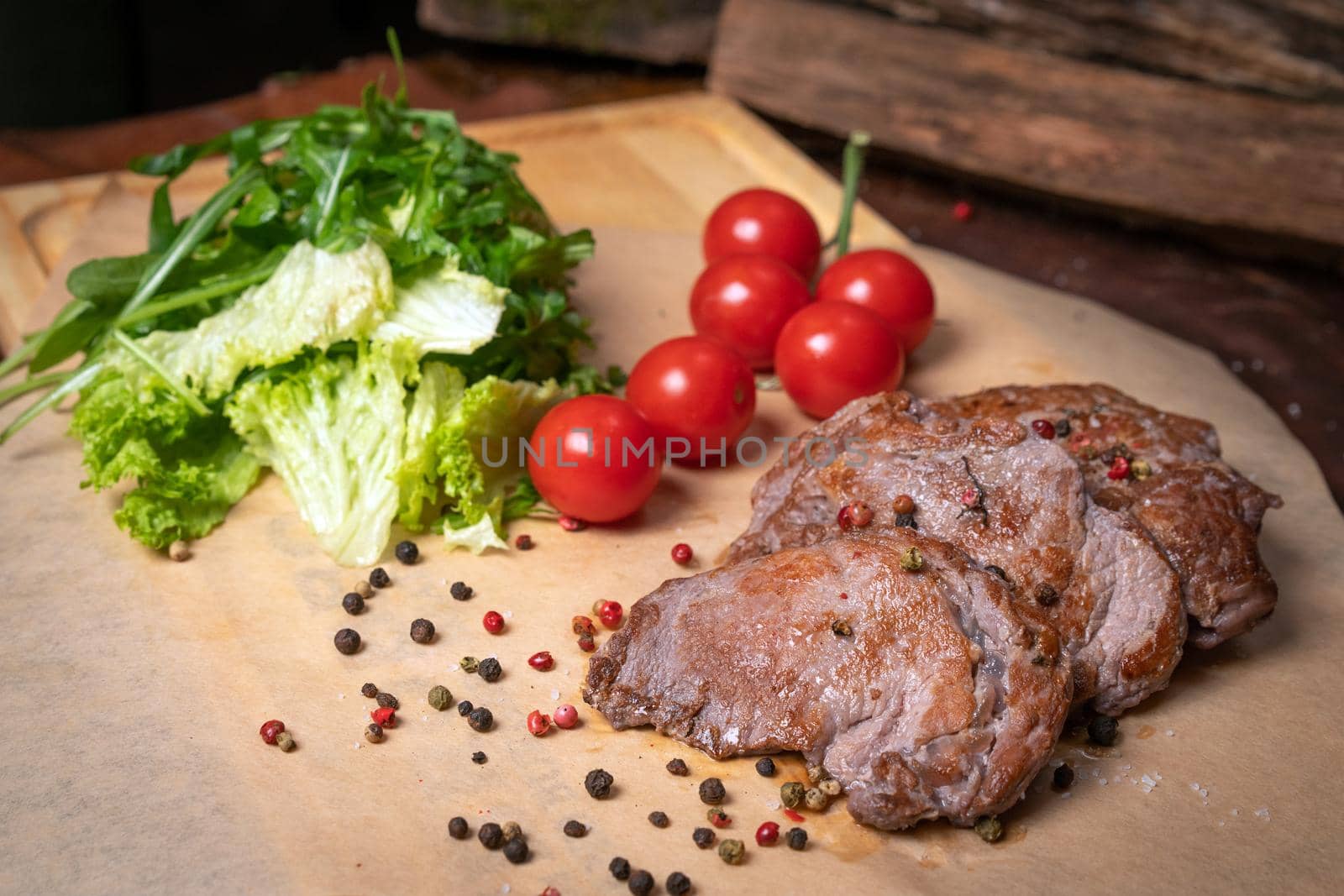 Pork fillets are served with barbecue sauce, soy sauce, cherry tomatoes, lettuce salad with arugula-seeded pepper mixture. Restaurant concept. Restaurant food. Grill concept.