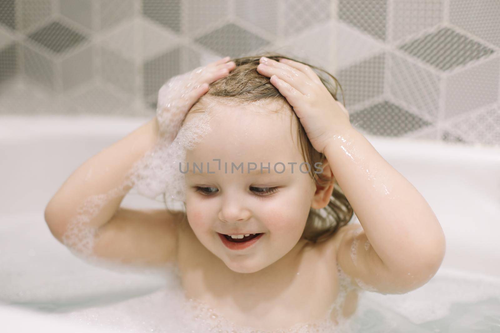 Child bathing. Little baby taking bath, closeup face portrait of smiling girl, health care and kids hygiene. 