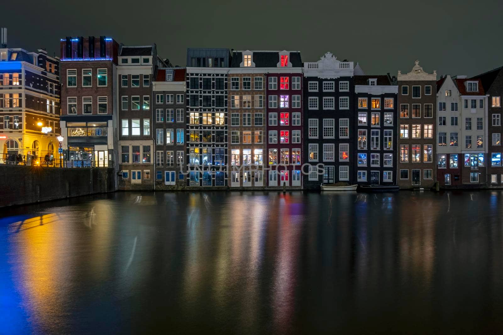 Traditonal houses at the Damrak in Amsterdam in the Netherlands by night by devy