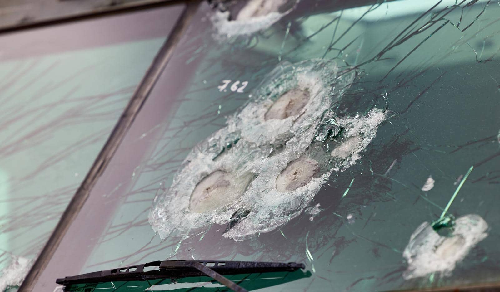 Armored glass after of a direct hit from an automatic weapon. Safety glass after being hit by a bullet. Bulletproof glass armored car after gunshot.