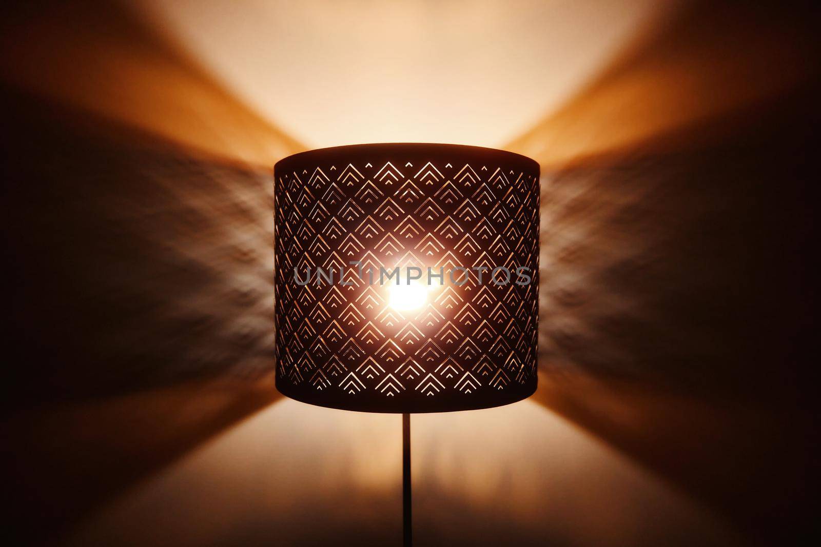 Floor lamp light. Rays of light through the holes in the lamp floor lamp. Bright shining lamp in the night.