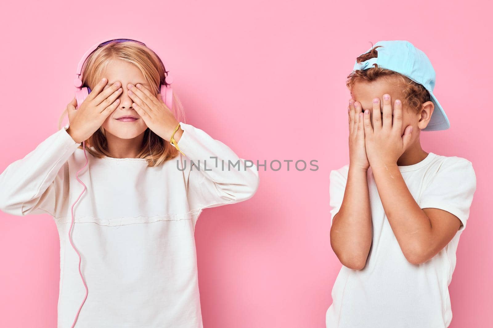 a boy in a cap and a girl standing side by side posing fashion isolated background by SHOTPRIME