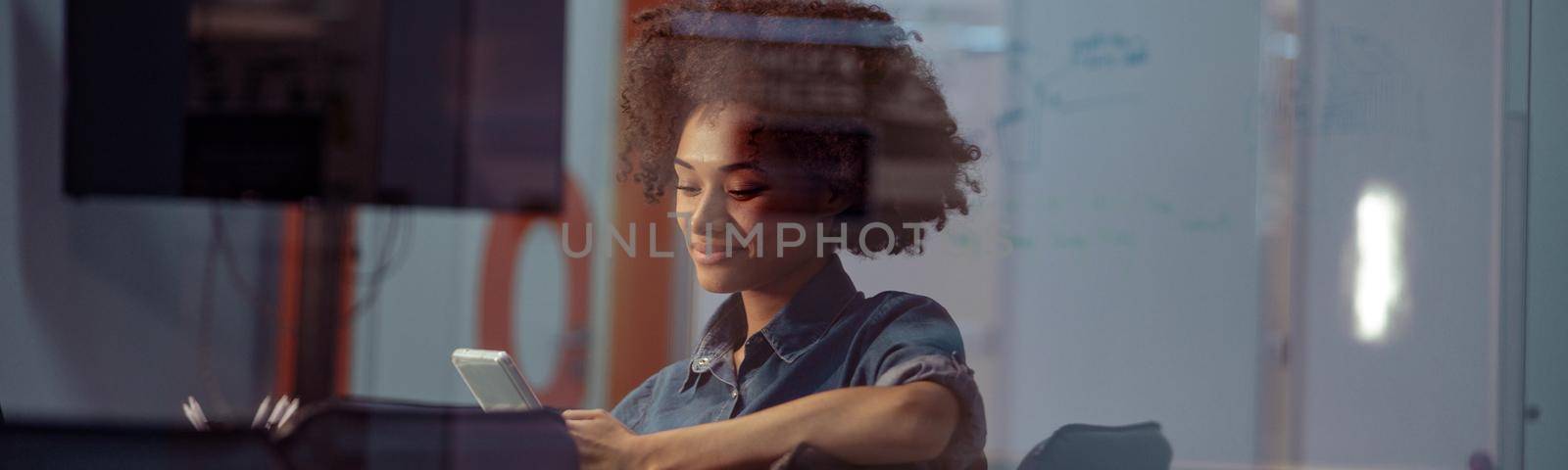 Happy young lady holding mobile phone in the office by Yaroslav_astakhov