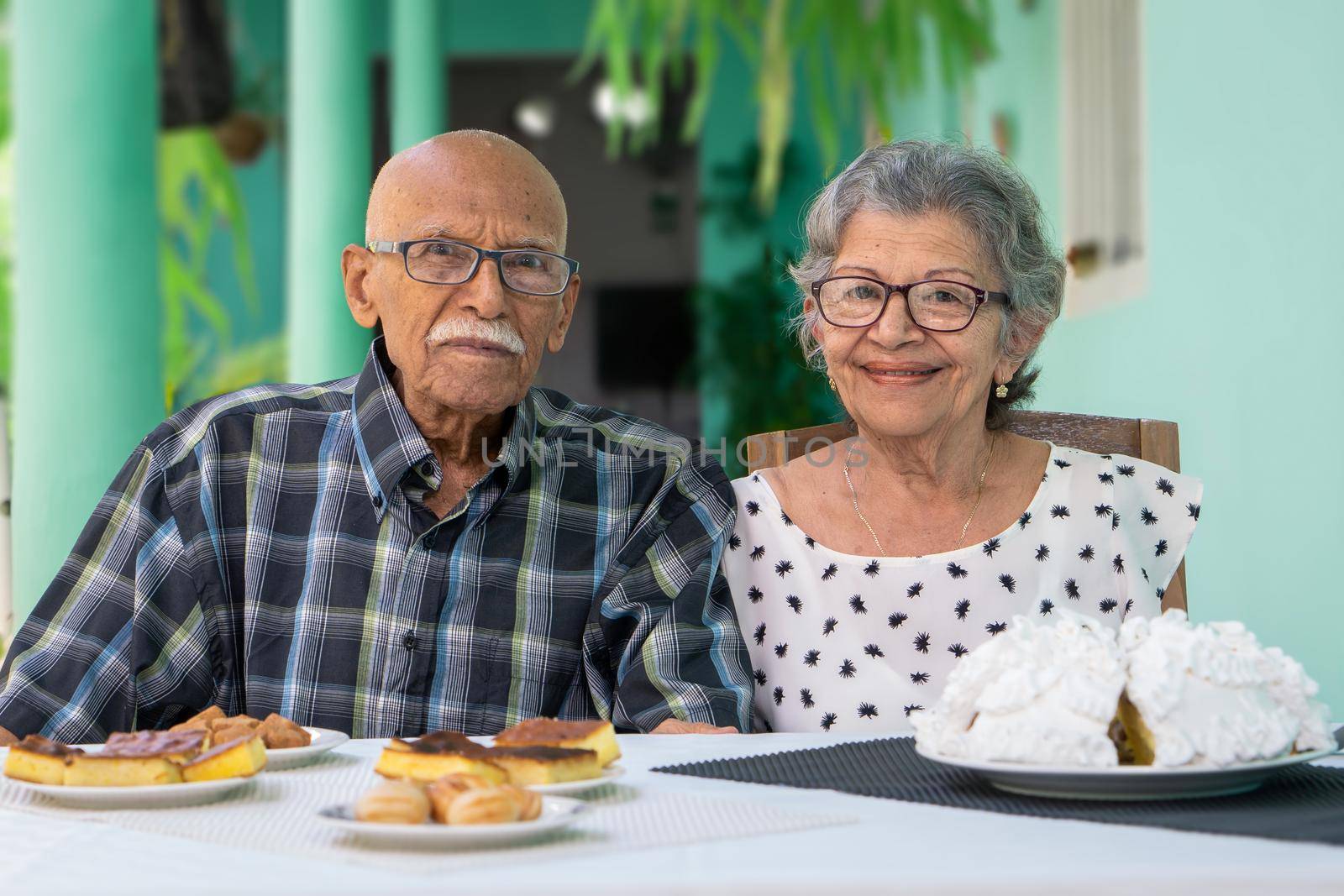 Elderly couple wearing eyeglasses sitting at a table looking at the camera