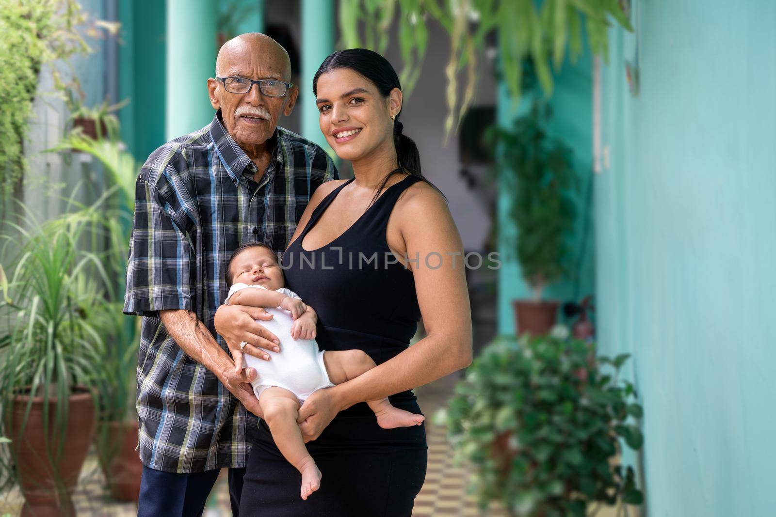 Photo of a baby carried in the arms of a woman and an elderly man