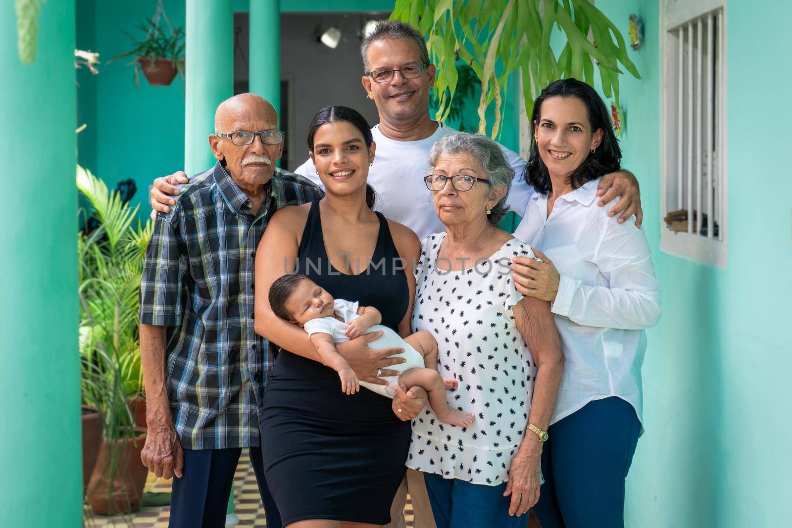 Photo of a group of people. A baby in the arms of a young woman, a man, a woman and an elderly couple