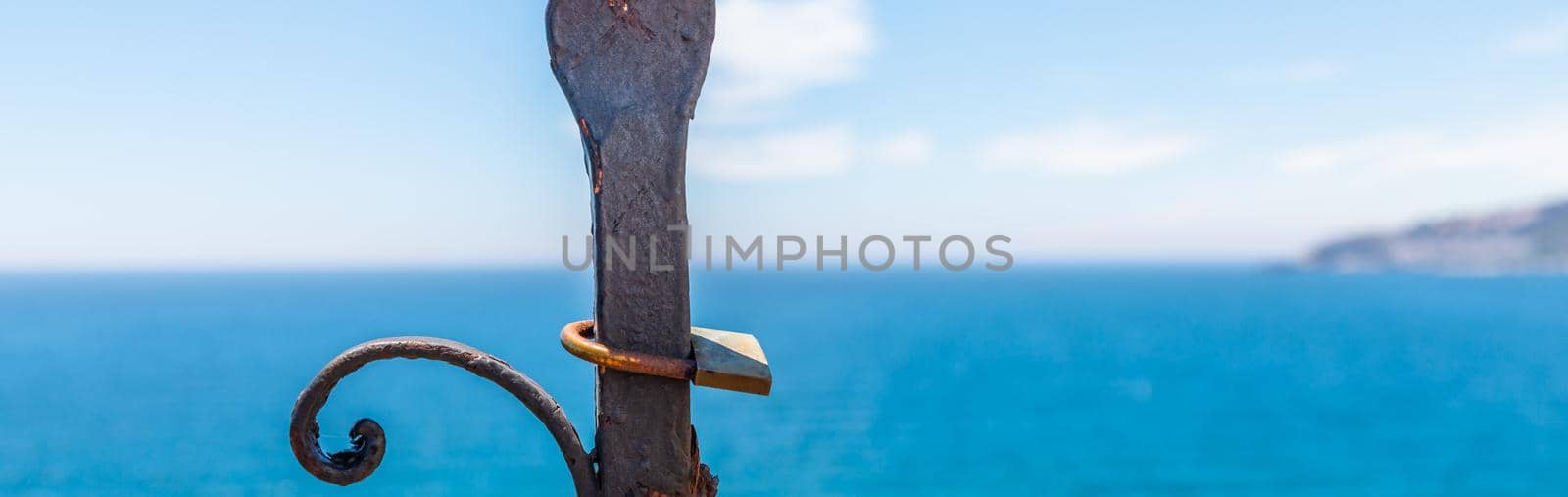 rusty padlock attached to a balustrade by the sea, a traditional way of showing love by Q77photo